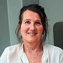 Kvinne i hvit skjorte smiler foran kameraet