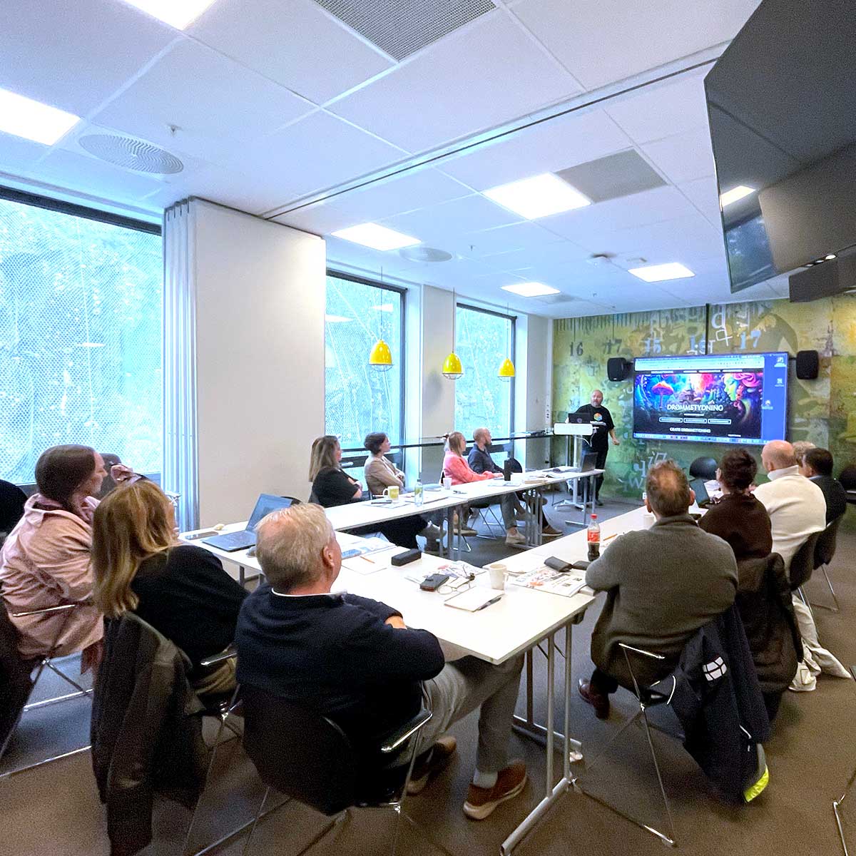 Møte i konferanserom med presentasjon på skjerm.